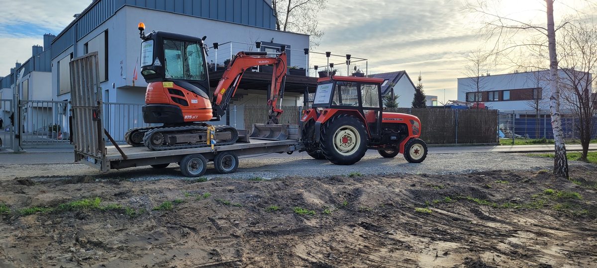 Minikoparka na lawecie transportowej za ciągnikiem